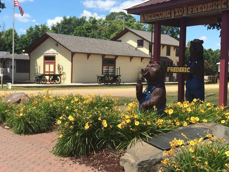 The depot museum with a carved wooden bear and daylilies out front